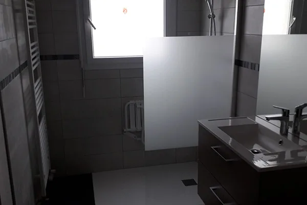 Salle de bains rénovée : meuble vasque noir et paroi de douche en verre dépoli