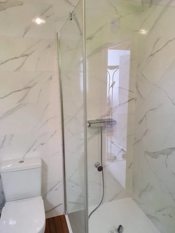 Douche aux murs effet marbre et WC dans une salle de bains rénovée