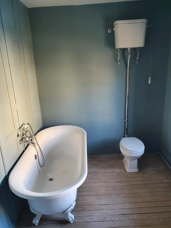Salle de bains aux murs bleus avec baignoire sur pieds et WC à chasse haute