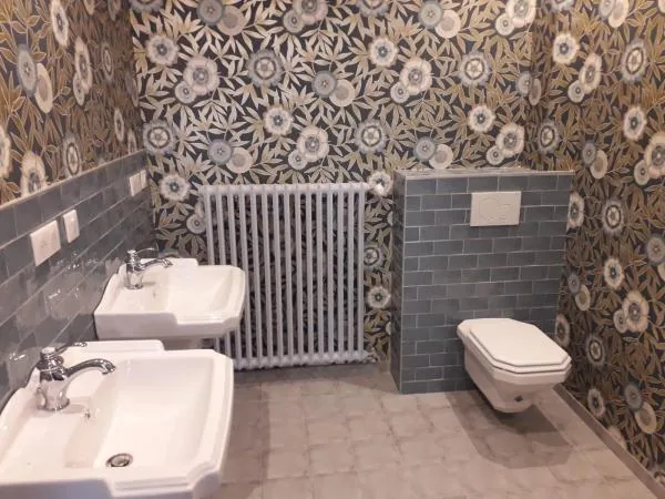 Salle d’eau avec lavabo, radiateur et WC suspendu devant un papier peint à motifs