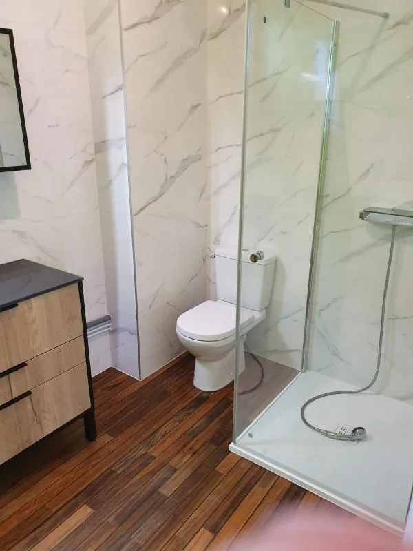 Salle de bains avec WC, meuble en bois et douche à l’italienne