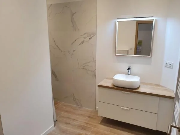 Meuble vasque en bois avec miroir lumineux devant un mur effet marbre