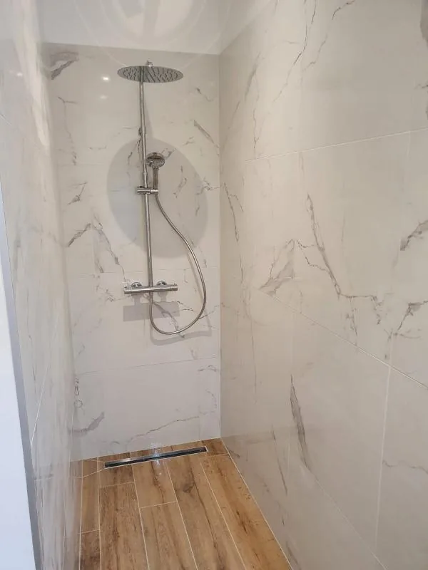 Douche à l’italienne avec colonne de douche et carrelage effet marbre