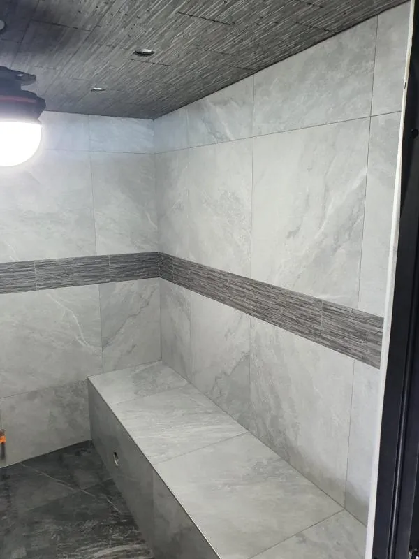 Douche carrelée en marbre blanc avec banc intégré